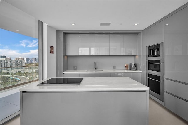 kitchen featuring stainless steel appliances, sink, gray cabinets, and a center island