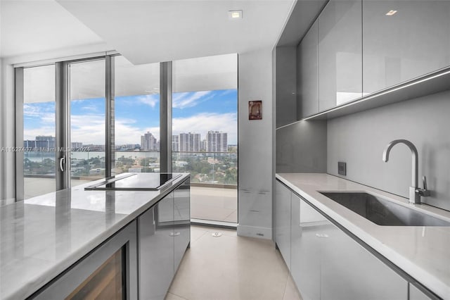 kitchen featuring sink, light tile floors, gray cabinetry, light stone countertops, and black electric stovetop