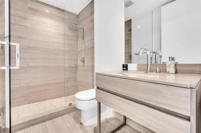 bathroom with toilet, a shower with door, and vanity