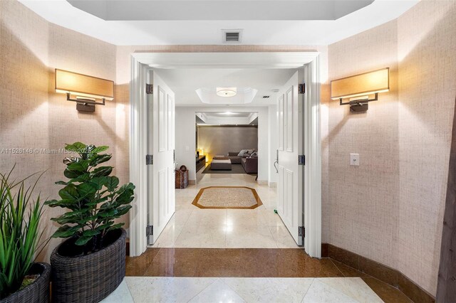 living room with tile flooring, crown molding, and a tray ceiling