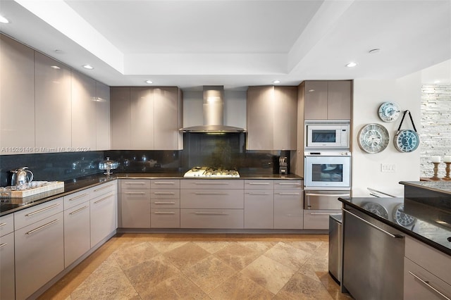 kitchen featuring light tile floors, gray cabinetry, tasteful backsplash, and wall chimney range hood