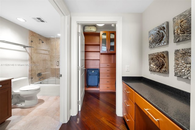 full bathroom with tiled shower / bath, toilet, tile flooring, and vanity