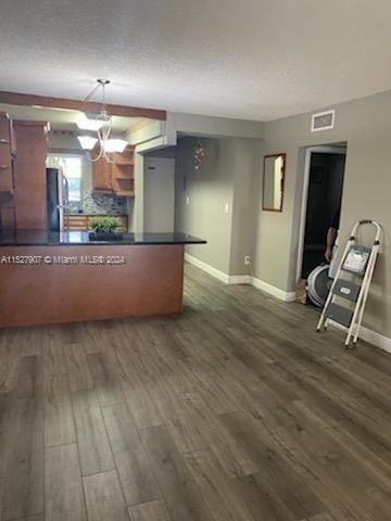 kitchen featuring dark hardwood / wood-style floors, hanging light fixtures, stainless steel refrigerator, tasteful backsplash, and a notable chandelier