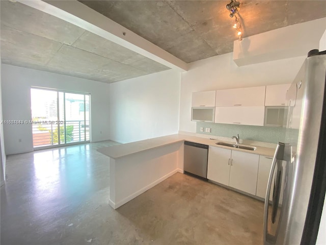 kitchen featuring sink, rail lighting, appliances with stainless steel finishes, white cabinetry, and concrete flooring