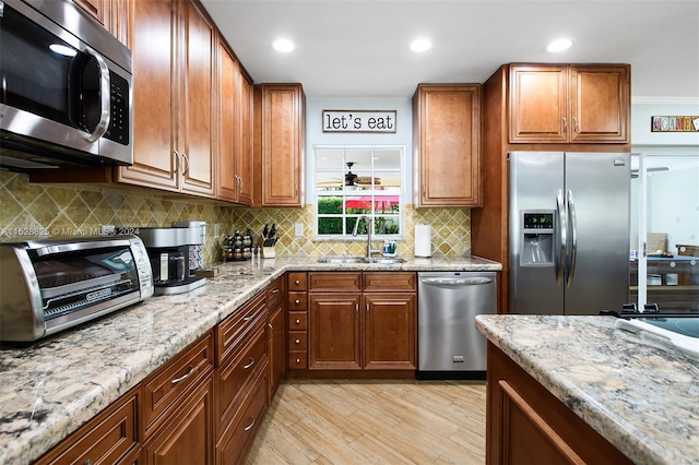 kitchen featuring sink, light stone counters, light hardwood / wood-style flooring, backsplash, and stainless steel appliances