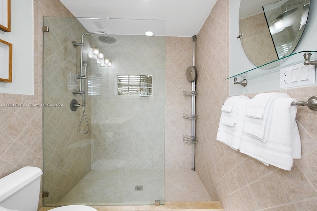 bathroom with tile walls, toilet, and a tile shower