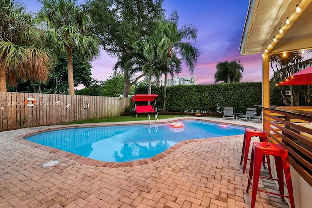 pool at dusk featuring a patio area