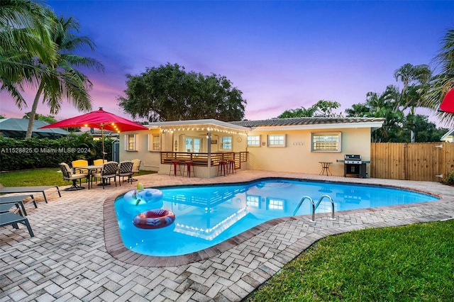 pool at dusk featuring a patio area and a pergola