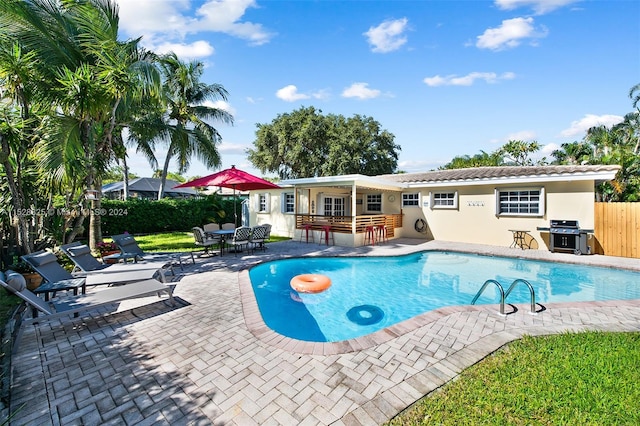 view of swimming pool with grilling area and a patio area