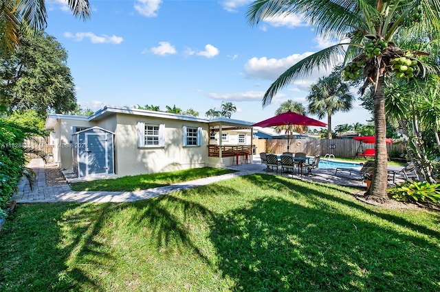 back of house featuring a yard, a fenced in pool, and a patio area