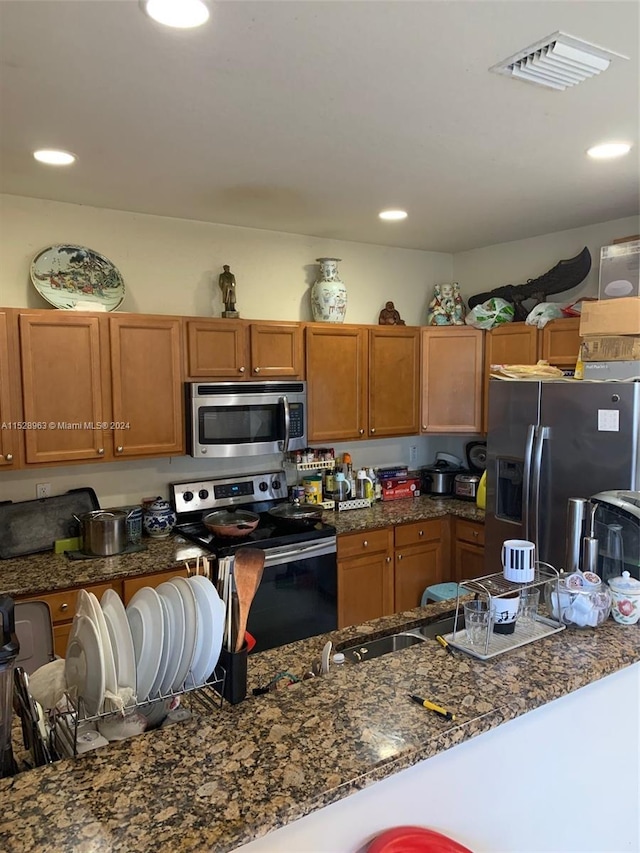 kitchen featuring stainless steel appliances and dark stone countertops