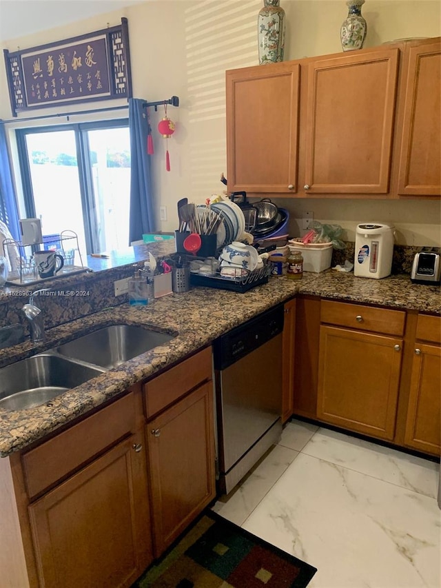 kitchen with dark stone countertops, light tile floors, dishwasher, and sink