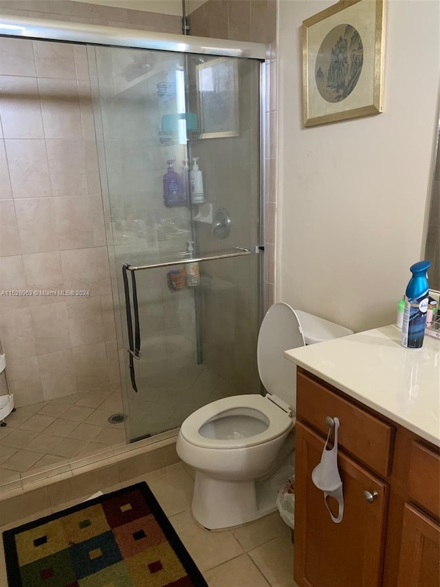 bathroom with vanity, tile floors, a shower with shower door, and toilet