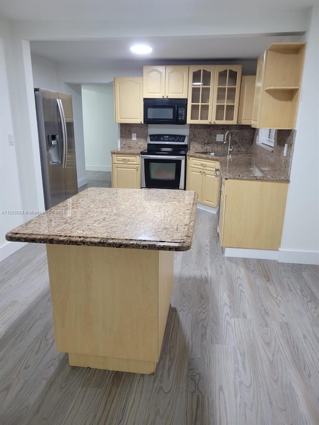 kitchen featuring a kitchen island, light wood-type flooring, stainless steel appliances, and light brown cabinetry