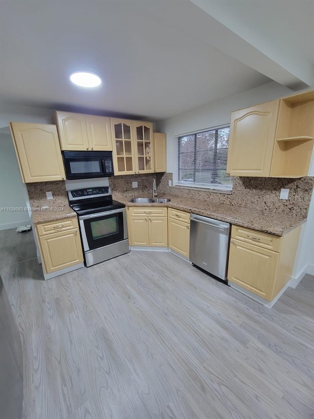 kitchen featuring light wood-type flooring, light stone counters, stainless steel appliances, sink, and light brown cabinets