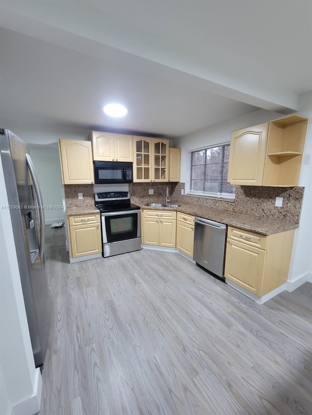 kitchen featuring dark stone counters, sink, light wood-type flooring, light brown cabinetry, and appliances with stainless steel finishes