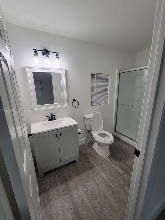 bathroom with hardwood / wood-style floors, vanity, toilet, and an enclosed shower