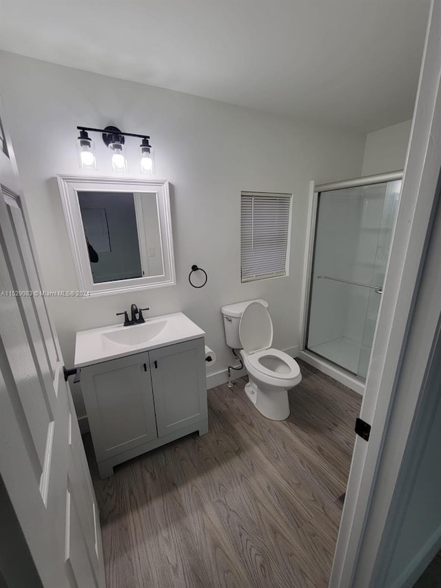 bathroom with toilet, a shower with door, vanity, and hardwood / wood-style flooring