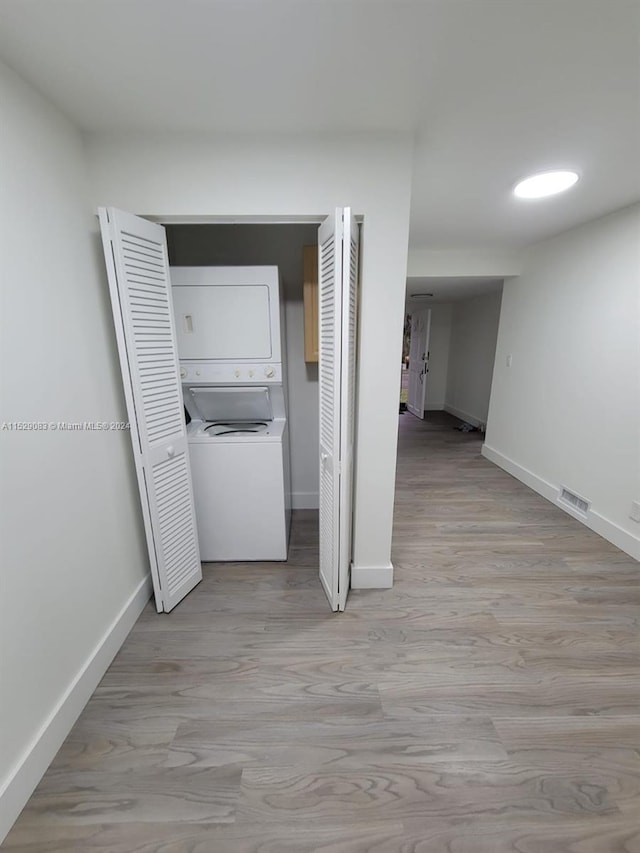 hall featuring stacked washer and dryer and light wood-type flooring