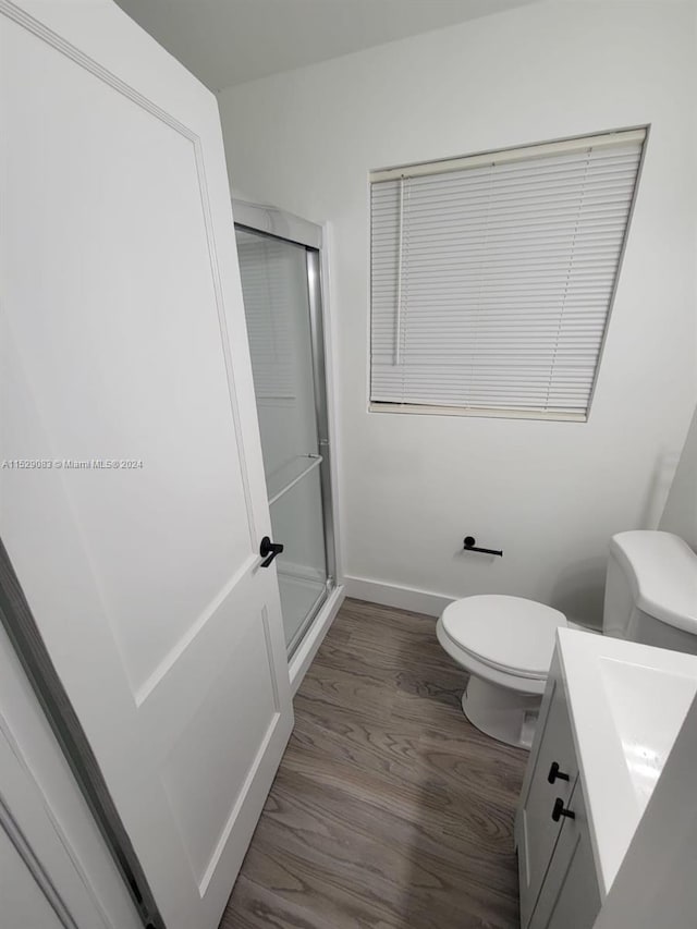 bathroom with vanity, toilet, wood-type flooring, and a shower with shower door