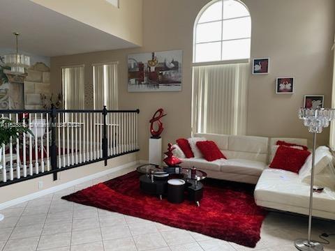 tiled living room with a high ceiling and a notable chandelier