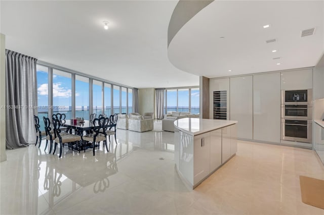 kitchen featuring double oven, built in microwave, a center island, floor to ceiling windows, and a water view