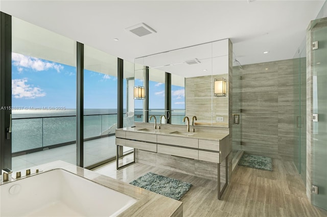 bathroom with expansive windows, shower with separate bathtub, a water view, and vanity