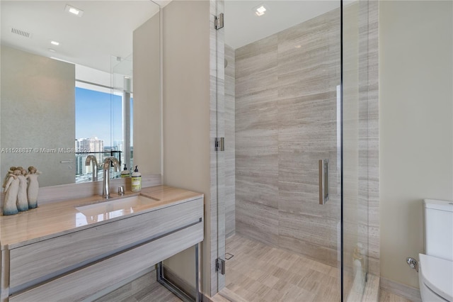 bathroom with walk in shower, vanity, and toilet