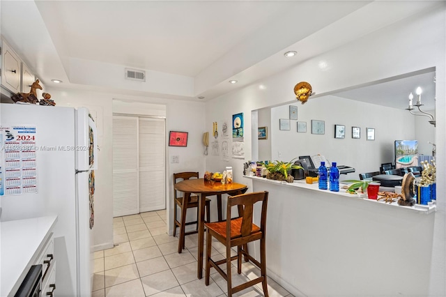 kitchen featuring light tile flooring, white fridge, and white cabinetry