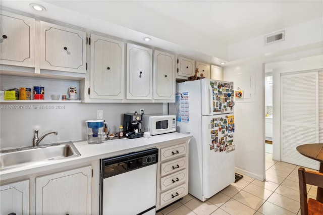 kitchen featuring light tile flooring, white appliances, and sink