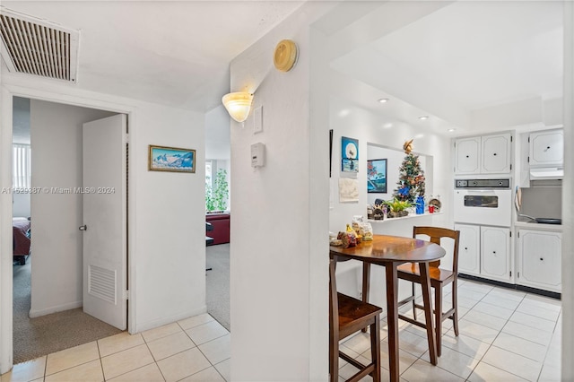 kitchen with light carpet, white oven, and white cabinetry