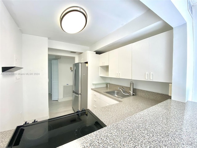 interior space with stove, stainless steel fridge, white cabinets, and sink