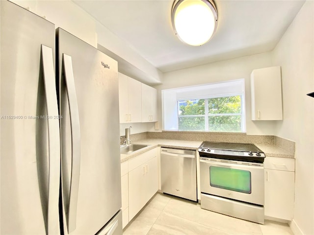 kitchen featuring light tile flooring, stainless steel appliances, white cabinetry, and sink