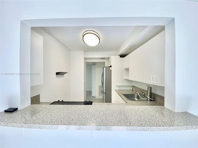 kitchen featuring stainless steel refrigerator, white cabinets, and sink