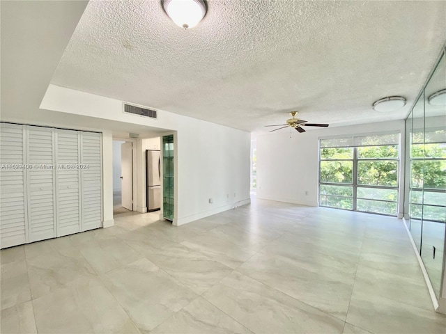 spare room featuring light tile floors, ceiling fan, and a textured ceiling