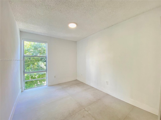 tiled empty room featuring a textured ceiling