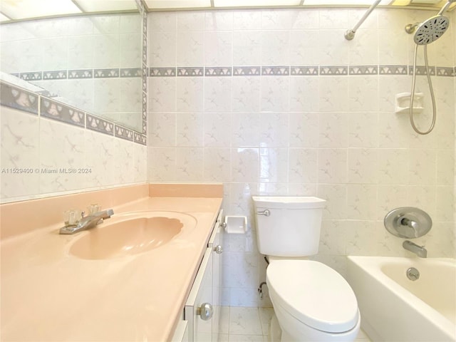 full bathroom featuring tiled shower / bath combo, large vanity, toilet, and tile walls