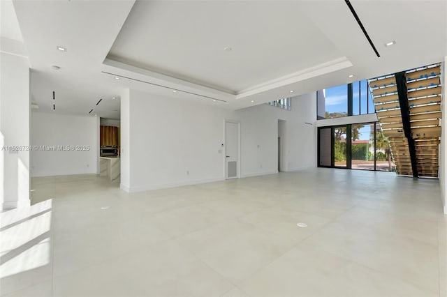 unfurnished living room featuring a tray ceiling and a high ceiling