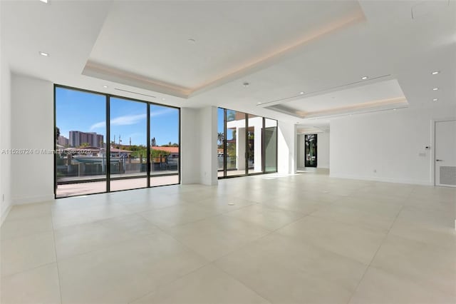 spare room with expansive windows, light tile patterned floors, and a raised ceiling