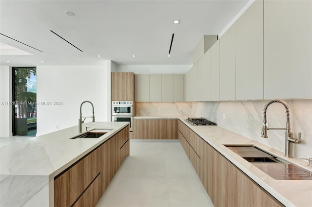 kitchen with sink, light stone countertops, tasteful backsplash, and stainless steel appliances