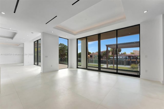 tiled spare room featuring floor to ceiling windows and a raised ceiling