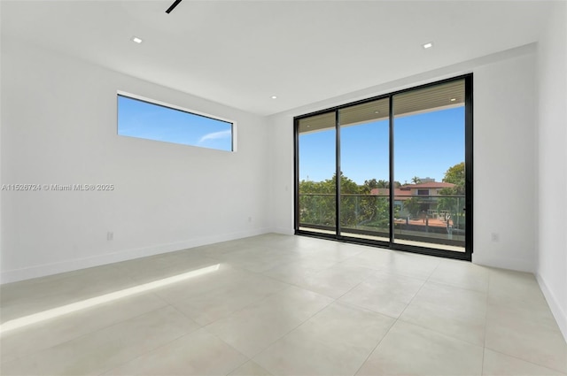 tiled empty room featuring plenty of natural light and expansive windows