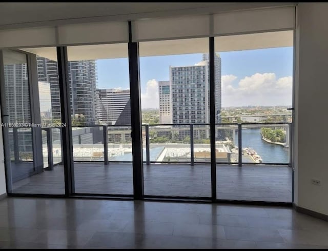 doorway with expansive windows, tile patterned flooring, and a water view