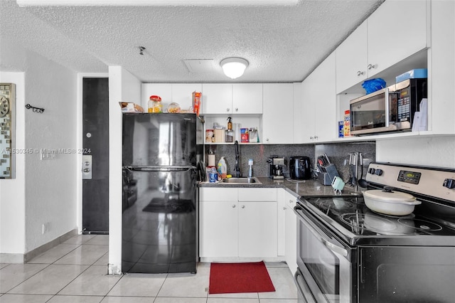 kitchen featuring a textured ceiling, appliances with stainless steel finishes, sink, white cabinetry, and light tile patterned flooring