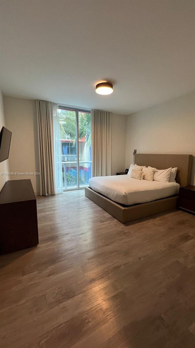 bedroom with hardwood / wood-style floors and access to outside