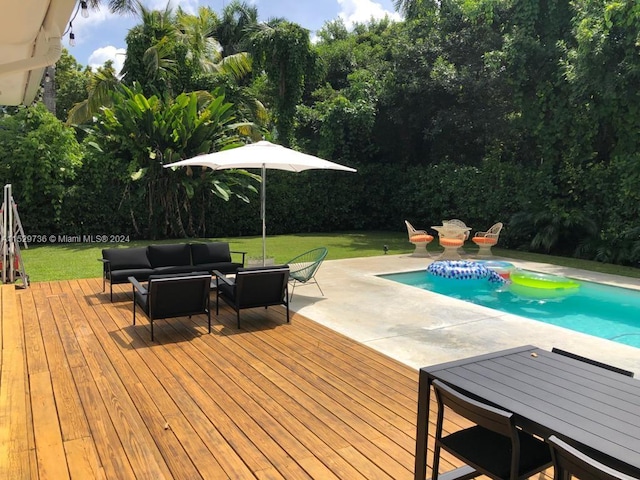 view of pool with an outdoor living space, a wooden deck, and a lawn