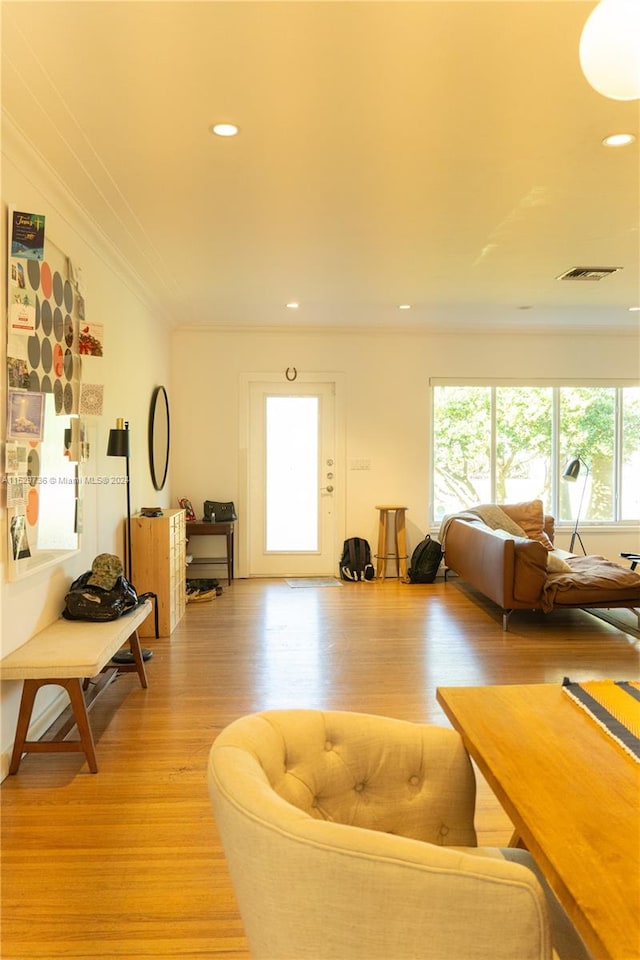 living room with ornamental molding, light hardwood / wood-style flooring, and a wealth of natural light