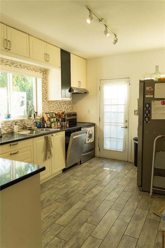 kitchen featuring appliances with stainless steel finishes, track lighting, tasteful backsplash, white cabinetry, and sink