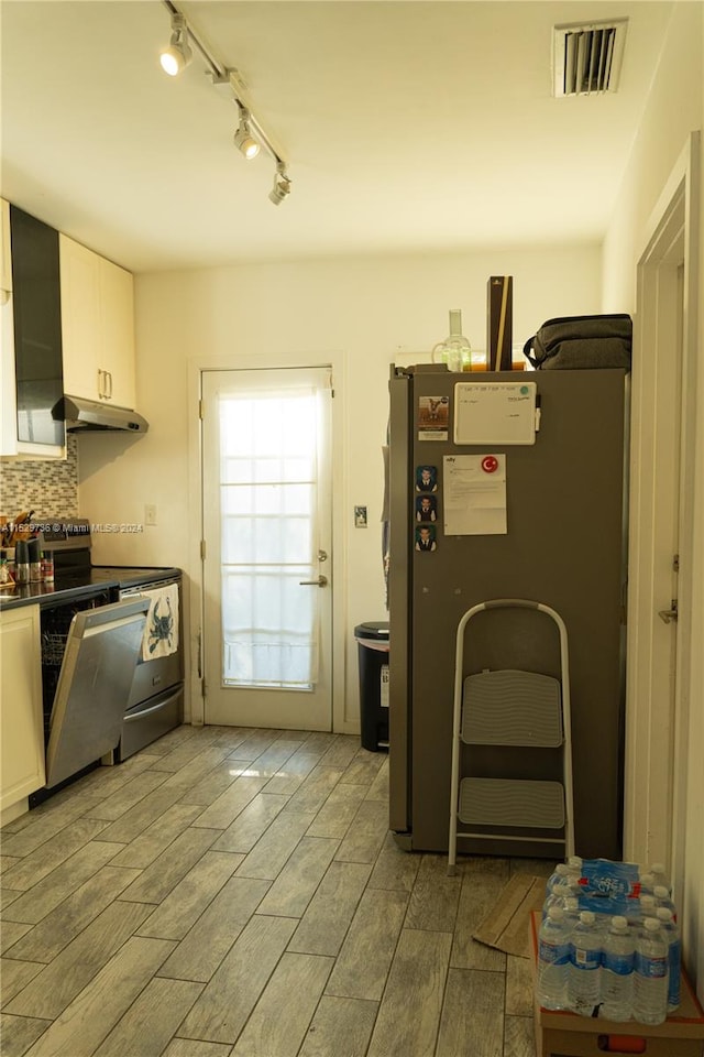 kitchen featuring white cabinets, fridge, range, tasteful backsplash, and track lighting