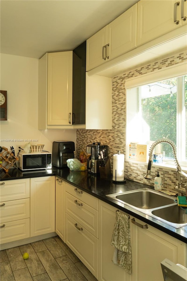 kitchen featuring backsplash, stainless steel microwave, white cabinets, and sink